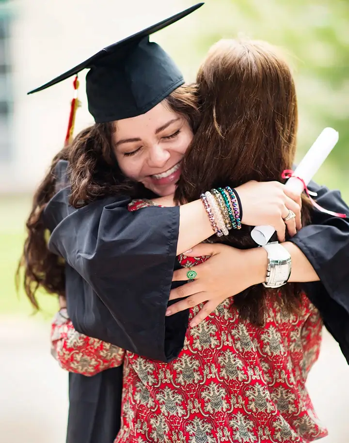 Happy graduate hugging woman